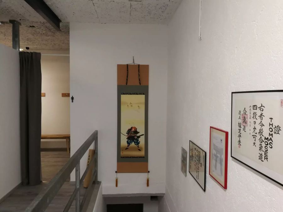 Umkleide und die Treppe hinab in den Trainingsraum. An der Wand hängen die Diplome von Thomas und Sandra Moser - original aus Japan.