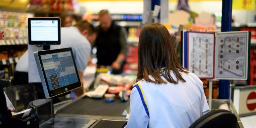 Kunden und Kassiererin an einer Supermarktkasse