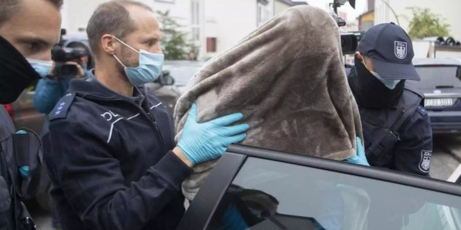 Beamte des Zoll führen den in Frankfurt festgenommenen Hauptbeschuldigten mit einer Decke über dem Kopf ab. Bei dem in Frankfurt festgenommenen Mann handelt es sich um einen Mann aus dem Umfeld der Hells-Angels. Foto: Boris Roessler/dpa