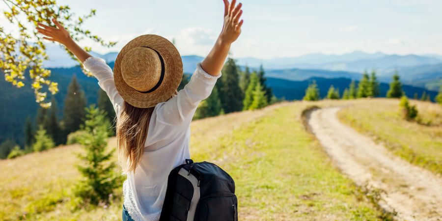 Urlauberin reckt in der Natur die Arme nach oben