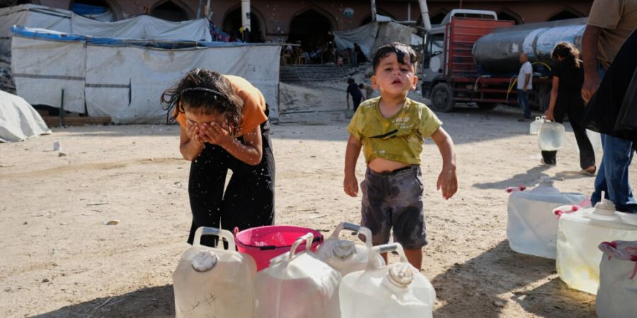 Vertriebene palästinensische Kinder kühlen sich in der Stadt Gaza in einem provisorischen Zeltlager mit Wasser ab. Foto: Jehad Alshrafi/AP/dpa
