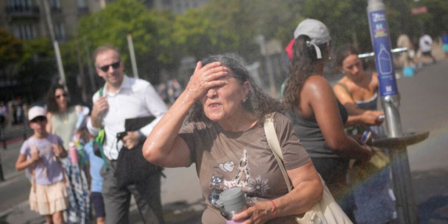 Touristen erfrischen sich an einem öffentlichen Trinkbrunnen in Paris. Foto: Christophe Ena/AP/dpa/Archivbild