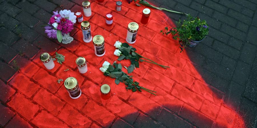 Kerzen und Blumen liegen in einem auf das Pflaster gesprühten roten Herzen in Düsseldorf nach dem mörderischen Brandanschlag.