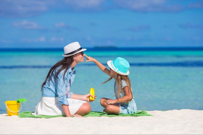 Dermatologen empfehlen Sonnencreme mit LSF 50+. Denn: Wer langsamer braun wird, schützt seine Haut besser. Mutter, Tochter, Strand