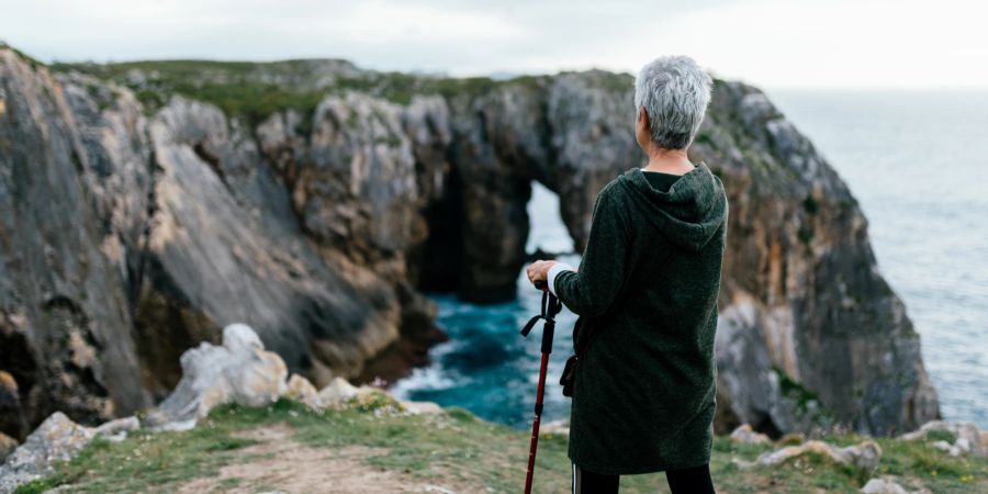 Frau mit Stock wandert am Meer