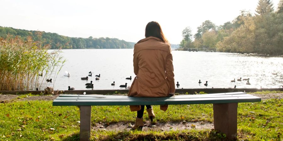 Frau auf Parkbank am See