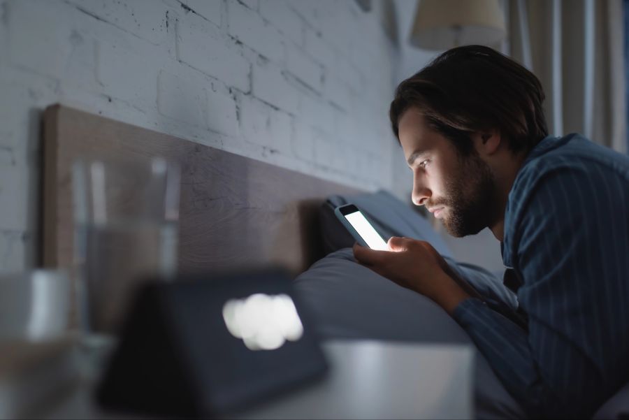 Mann mit Smartphone im Bett