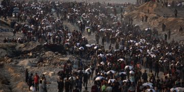 Displaced Palestinians carry bags of flour along Rashid Street in western Gaza City.