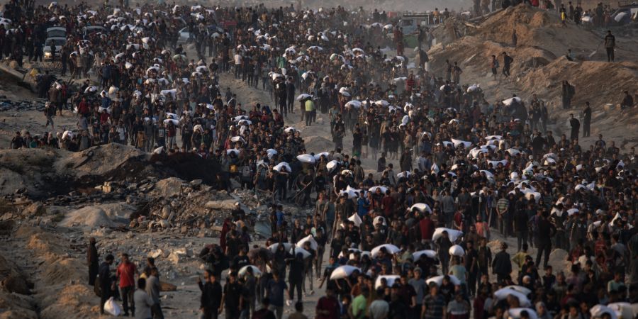 Displaced Palestinians carry bags of flour along Rashid Street in western Gaza City.