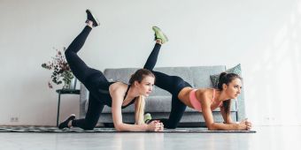 frauen machen sport auf matte, couch im hintergrund, weisser raum