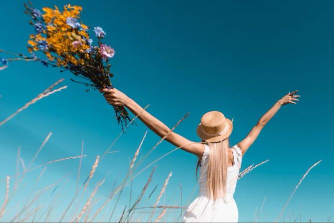 Frau im Feld mit Blumen, Freiheit, blauer Himmel, Sommer.