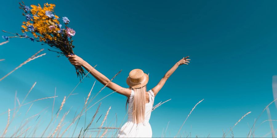 Frau im Feld mit Blumen, Freiheit, blauer Himmel, Sommer.