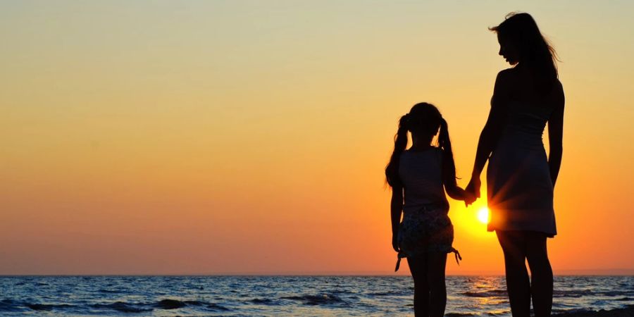 Mutter und Tochter halten Hand am Strand Sonnenuntergang