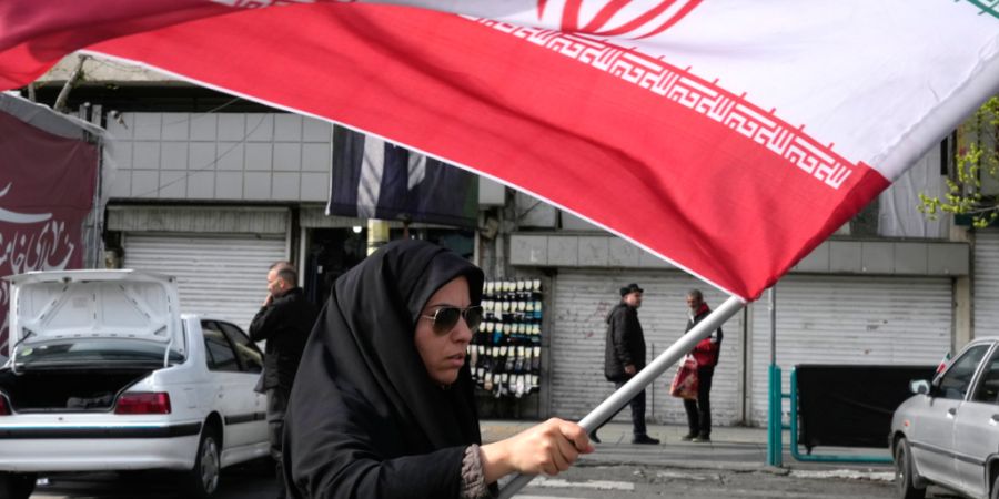 ARCHIV - Eine Frau schwenkt eine iranische Flagge während einer Kundgebung zur Unterstützung der Regierung auf dem Enqelab-e-Eslami-Platz (Platz der Islamischen Revolution). Foto: Vah...