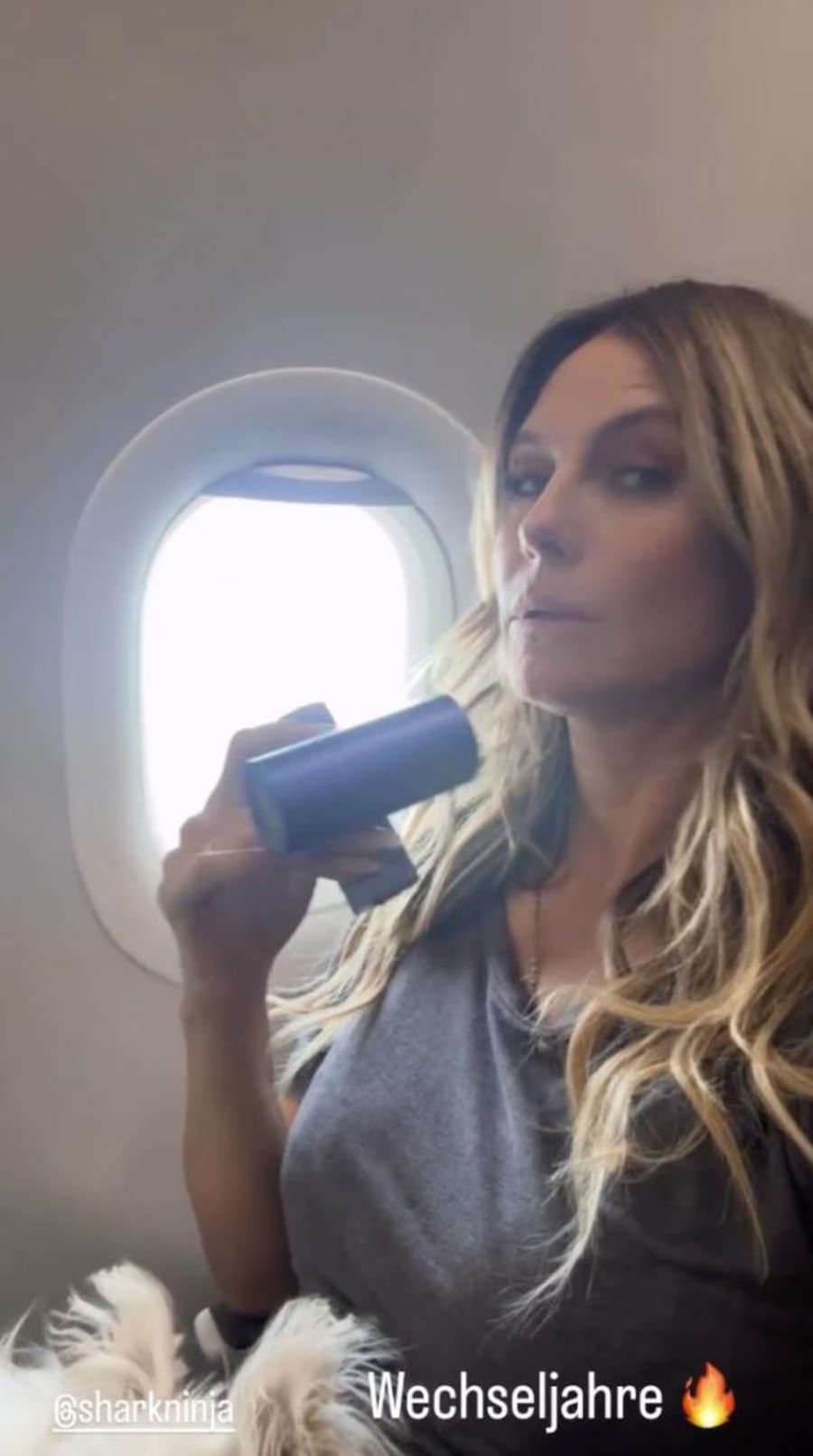 Im Flugzeug gegen Hitzewallungen gewappnet: Topmodel Heidi Klum greift zum Föhn.