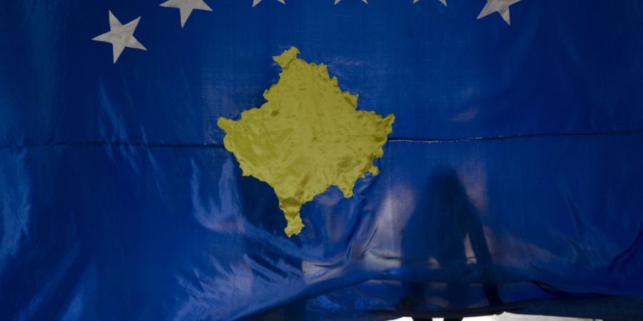 ARCHIV - 16.02.2018, Kosovo, Pristina: Zwei Schüler der Hasan Zyko Kamberi Schule halten bei einer Zeremonie zum zehnten Jahrestag der Unabhängigkeit des Kosovo eine Nationalflagge de...