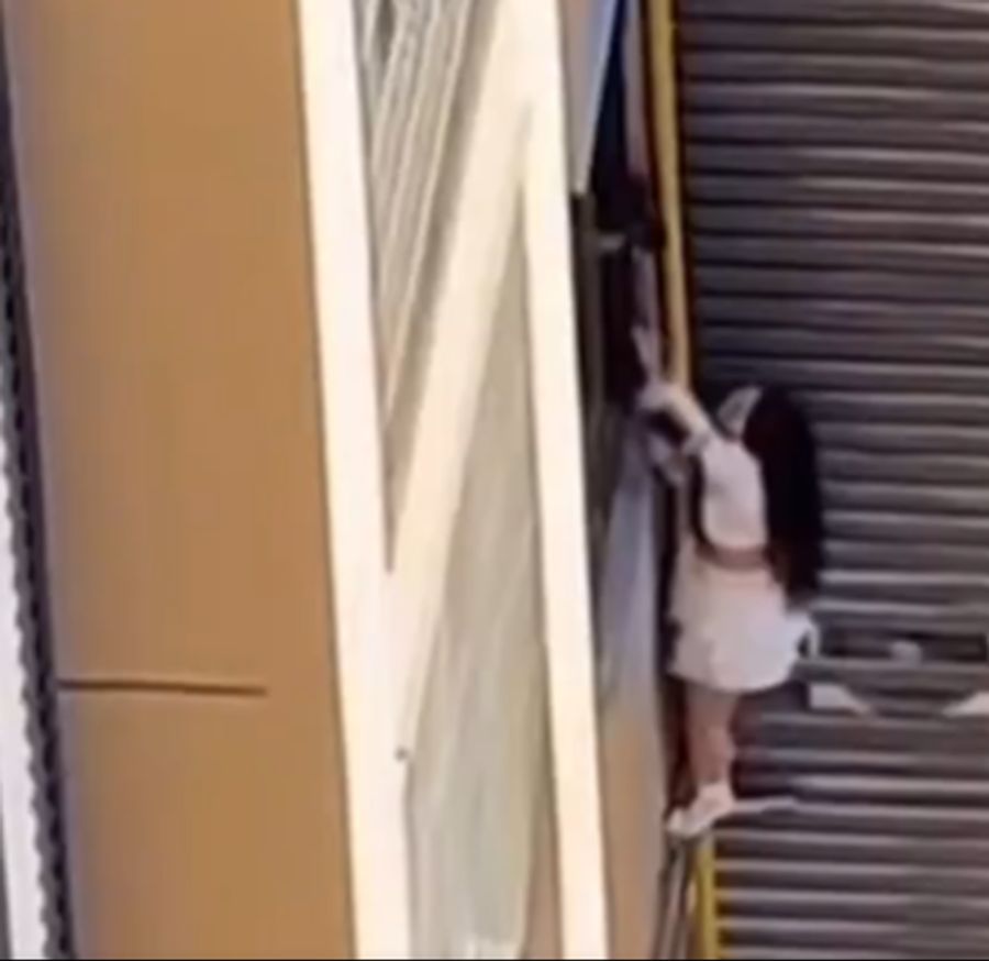 Ein Nachbar zieht die Frau wieder zurück in das Gebäude.