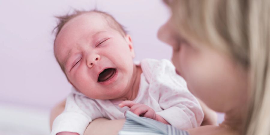 Weinendes Baby auf dem Arm der Mutter