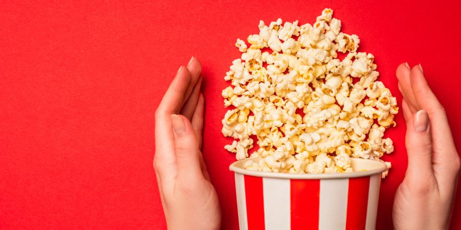 frauenhände halten popcornschachtel, roter hintergrund