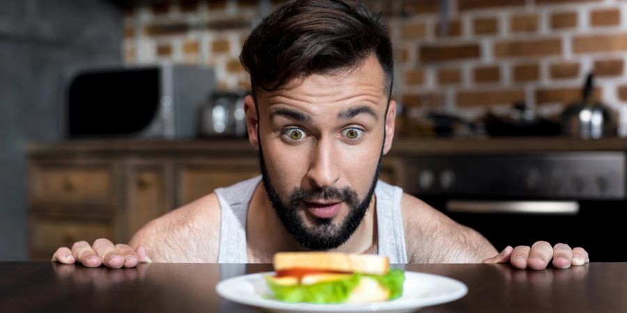 junger mann mit aufgerissenen augen vor essen