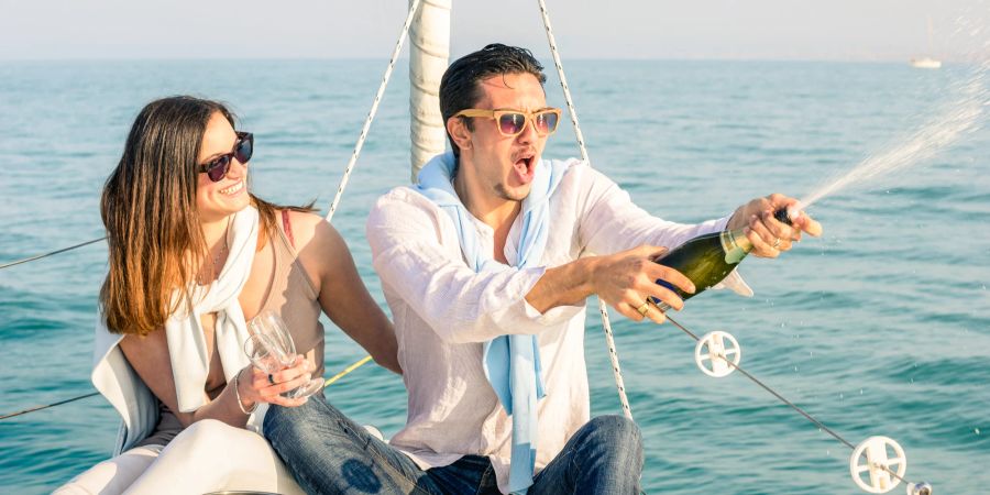 Mann und Frau sprühen Champagner an Bord.