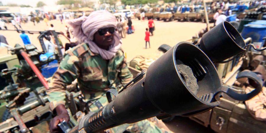 Ein Milizionär sitzt neben militärischer Ausrüstung, die angeblich während eines Gefechts im umkämpften Gebiet in Süd-Darfur erbeutet wurde.