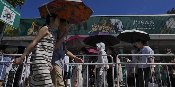 Zoobesucher in Peking schützen sich mit Regenschirmen vor der Sonne. Foto: Andy Wong/AP Zoobesucher in Peking schützen sich mit Regenschirmen vor der Sonne. Foto: Andy Wong/AP