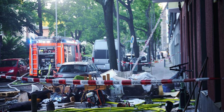 Verbranntes Mobiliar liegt auf einem Gehweg unterhalb einer ausgebrannten Wohnung in Berlin-Wilmersdorf.