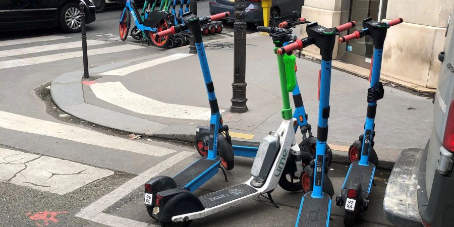 E-Scooter von drei verschiedenen Anbietern stehen auf dafür vorgesehenen Parkplätzen.