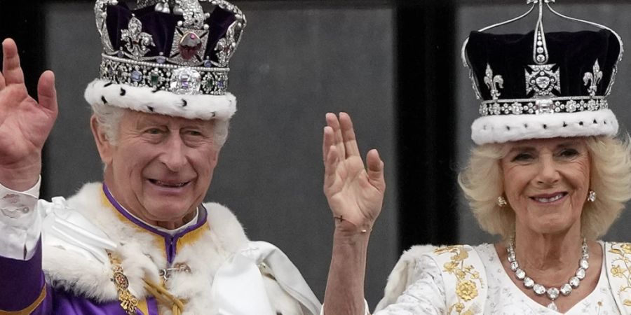 Grossbritanniens König Charles III. und Königin Camilla winken der Menge vom Balkon des Buckingham Palace nach der Krönungszeremonie zu. Foto: Frank Augstein/AP/dpa