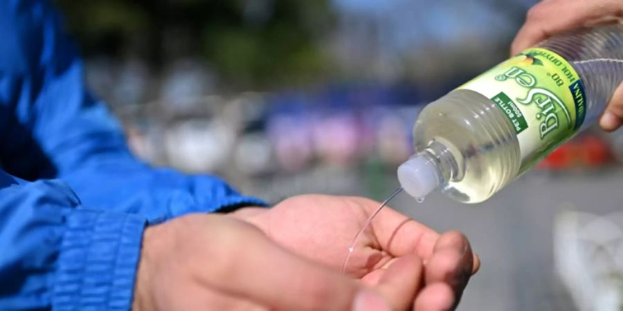 Ein Mann spritzt einem anderen Kölnisch Wasser in die Hände