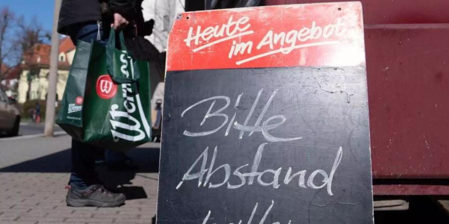 Ein Schild mit der Aufschrift «Bitte Abstand halten» auf einem Wochenmarkt. Foto: Sebastian Kahnert/dpa-Zentralbild/dpa