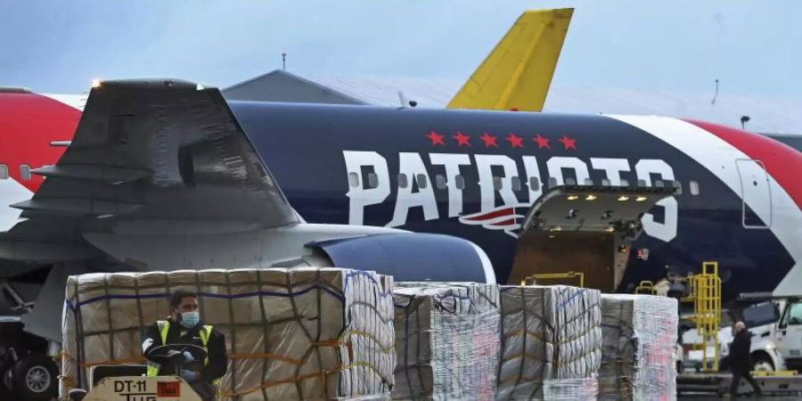 Paletten mit Atemschutzmasken werden aus dem Flugzeug der New England Patriots entladen. Foto: Jim Davis/Pool The Boston Globe/AP/dpa