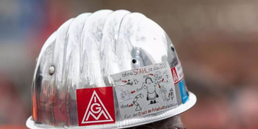 Das Logo der IG Metall auf dem Helm eines Stahlarbeiters. Foto: Bernd Thissen/dpa