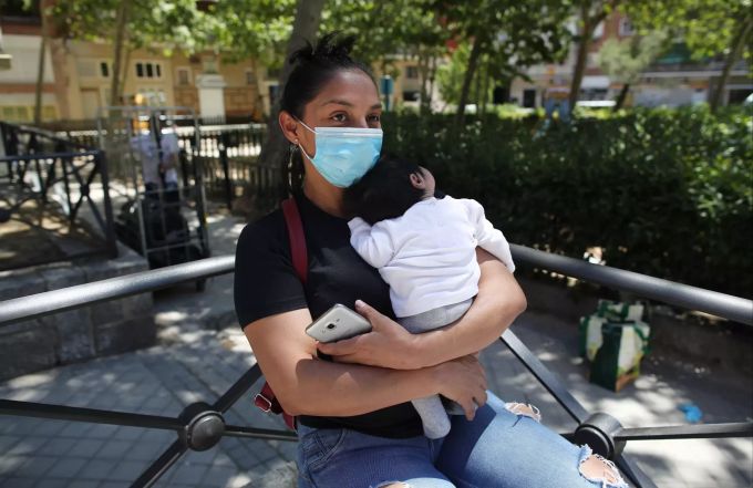 Eine Frau hält ihr Baby, während sie vor einer Kirche wartet, bis sie ein Paket mit Lebensmitteln erhält. In Spanien wird es für arme Familien erstmals ein monatliches «Grundeinkommen» geben. Spanien