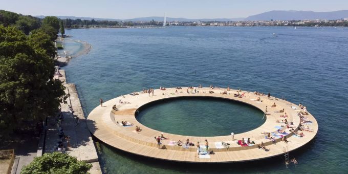 Menschen geniessen das schöne Wetter auf einer kreisförmigen Plattform mit 40 Meter Durchmesser, einer Installation am Ufer des Genfer Sees. Wetter Genfer See