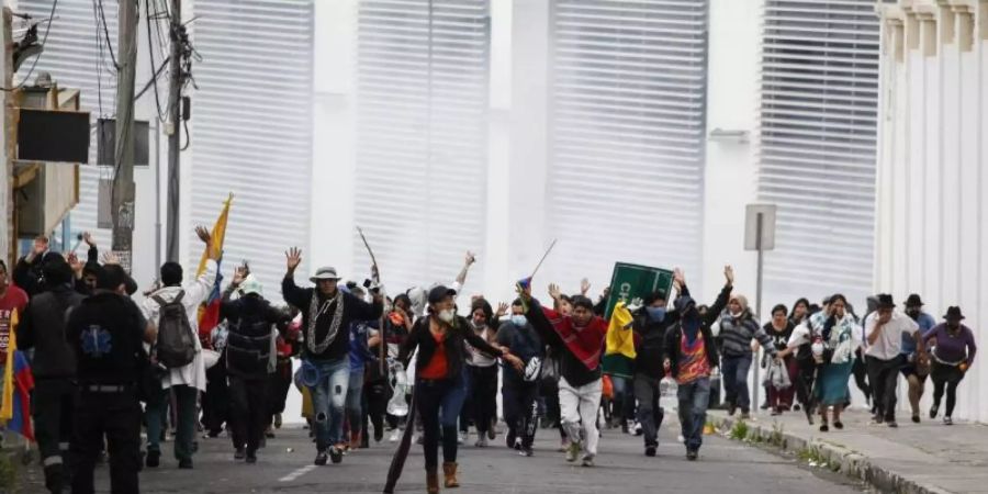 Teilnehmer einer Demonstration fliehen in Quito vor einer Wolke Tränengas. Foto: Juan Diego Montenegro/dpa