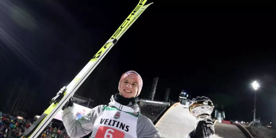 Karl Geiger jubelt mit dem silbernen Pokal für seinen zweiten Platz. Foto: Daniel Karmann/dpa
