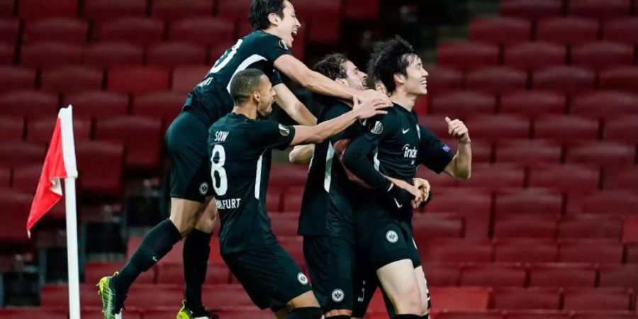 Die Frankfurter feiern den Treffer zum 2:1-Sieg beim FC Arsenal durch Daichi Kamada (r). Foto: Uwe Anspach/dpa