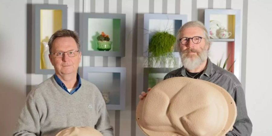 Die beiden Geschäftsführer der Firma Tutapets, Christian Wittmann (l) und Arno Ludwig vertreiben Tiersärge recyceltes Papier. Der Grafiker Arno Ludwig hat die Tiersärge in Katzen- und Meerschweinchenform entworfen. Foto: Nicolas Armer/dpa