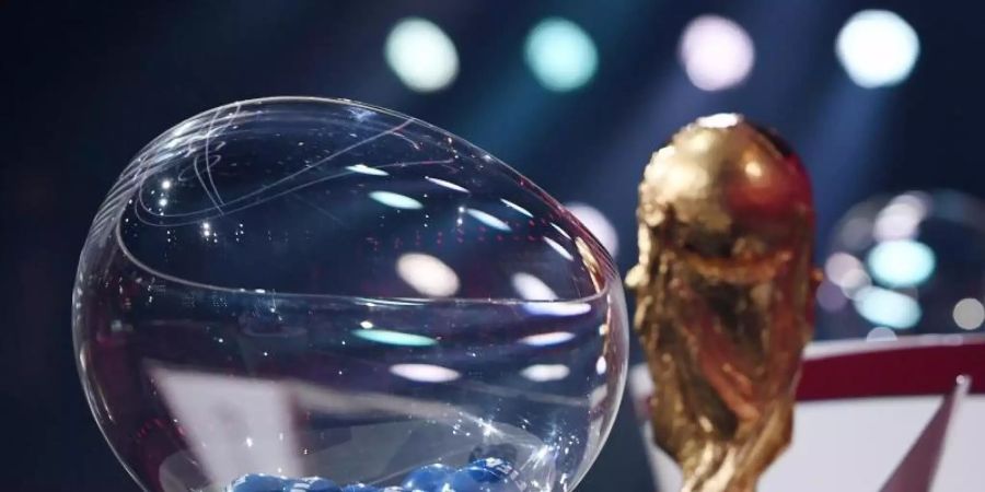 Der FIFA-WM-Pokal steht bei der Auslosung neben den Losen. Foto: Kurt Schorrer/FIFA/dpa