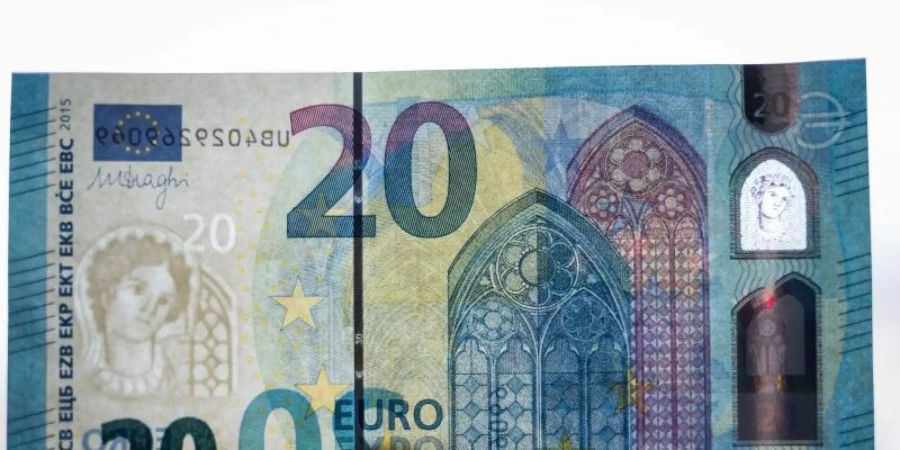 Ein Bundesbank-Mitarbeiter hält einen 20-Euro-Schein gegen das Licht. Foto: picture alliance / dpa