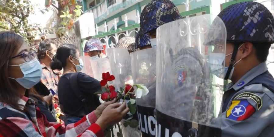 Demonstranten in Mandaley überreichen der Polizei Rosen, während vier festgenommene Aktivisten vor Gericht erscheinen. Foto: Uncredited/AP/dpa