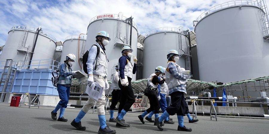 Journalisten werden an Tanks vorbei geführt, die behandeltes radioaktives Abwasser enthalten. Diese Tanks sind Teil der Anlage zur Ableitung von behandeltem radioaktivem Wasser aus dem Kernkraftwerk Fukushima Daiichi. Foto: Eugene Hoshiko/Pool AP/AP/dpa