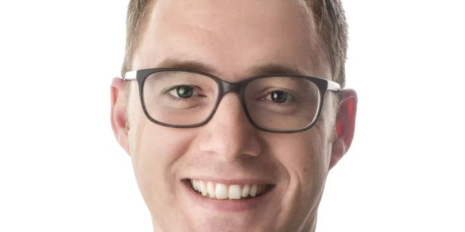Mann mit Brille und kurzen Haaren im Anzug