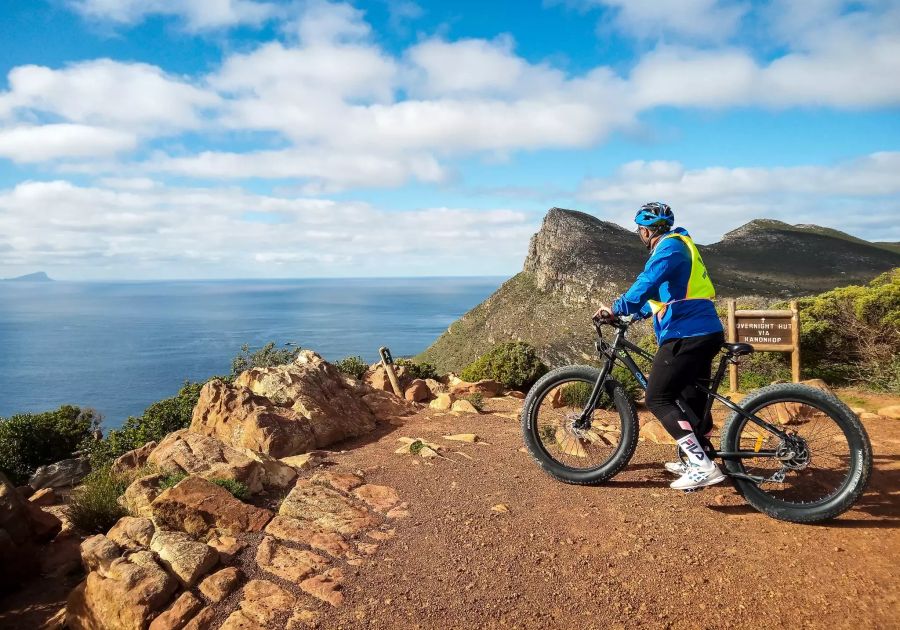 E-Biker auf Felsen vor Meer