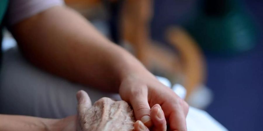 Ein Mann hält die Hand einer älteren Frau. Laut einer Umfrage würden zwei Drittel der 16- bis 39-Jährigen ihre Familienangehörigen pflegen. Foto: Jens Kalaene/dpa-Zentralbild/dpa-tmn/Archvi