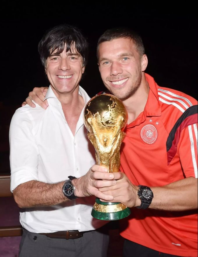 Lukas Podolski und Jogi Löw posieren mit dem WM-Pokal. Lukas Podolsli