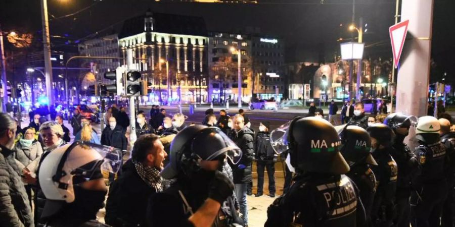 Demonstranten und Polizisten stehen in der Mannheimer Innenstadt. Trotz eines Verbots zogen in Mannheim nach Schätzungen der Polizei bis zu 2000 Menschen ohne Masken und ohne Abstand durch die Stadt. Foto: René Priebe/PR-Video/dpa