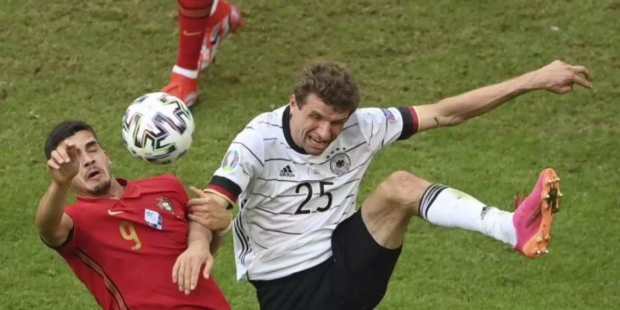 Thomas Müller (r) im Duell mit Portugals André Silva. Foto: Matthias Hangst/Pool Getty/dpa